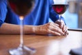 Woman is drinking red wine and having rest in cafe near window, close-up of womanÃ¢â¬â¢s hands holding glass on table Royalty Free Stock Photo